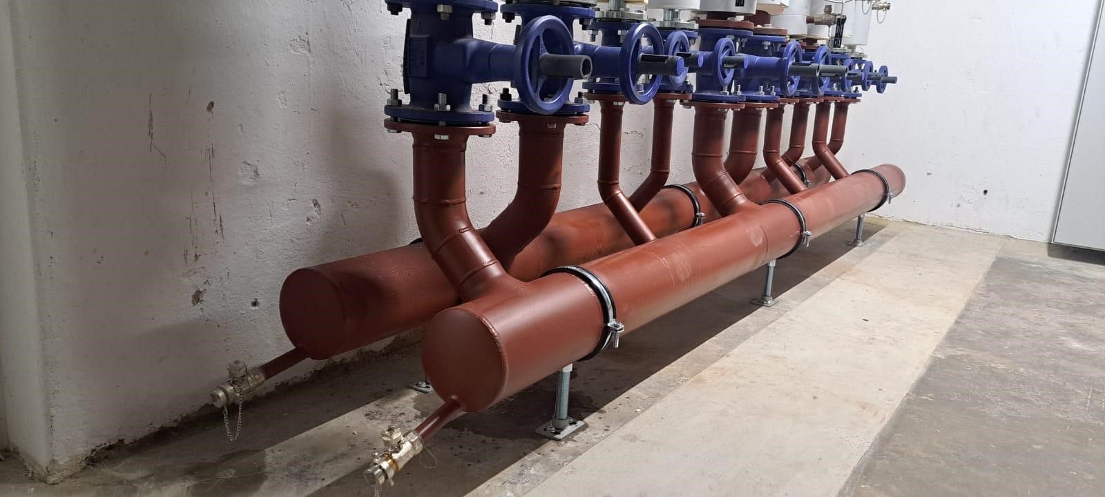 Eine Reihe von Rohren, die auf einem Betonboden in einem Raum liegen.