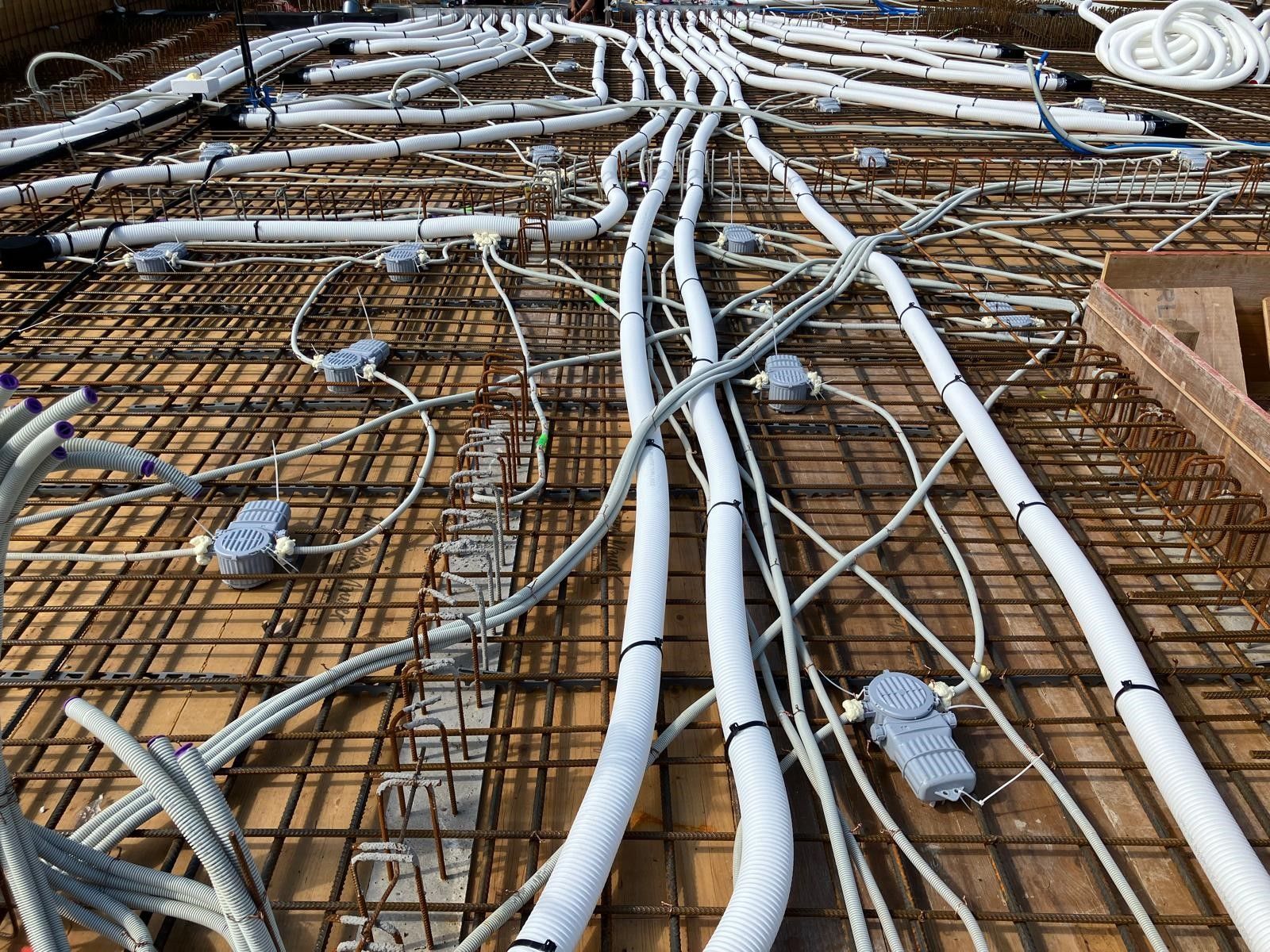 Auf einer Baustelle liegt ein Bündel Kabel auf dem Boden.