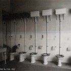 Ein Schwarzweißfoto einer Reihe Toiletten in einem Badezimmer.