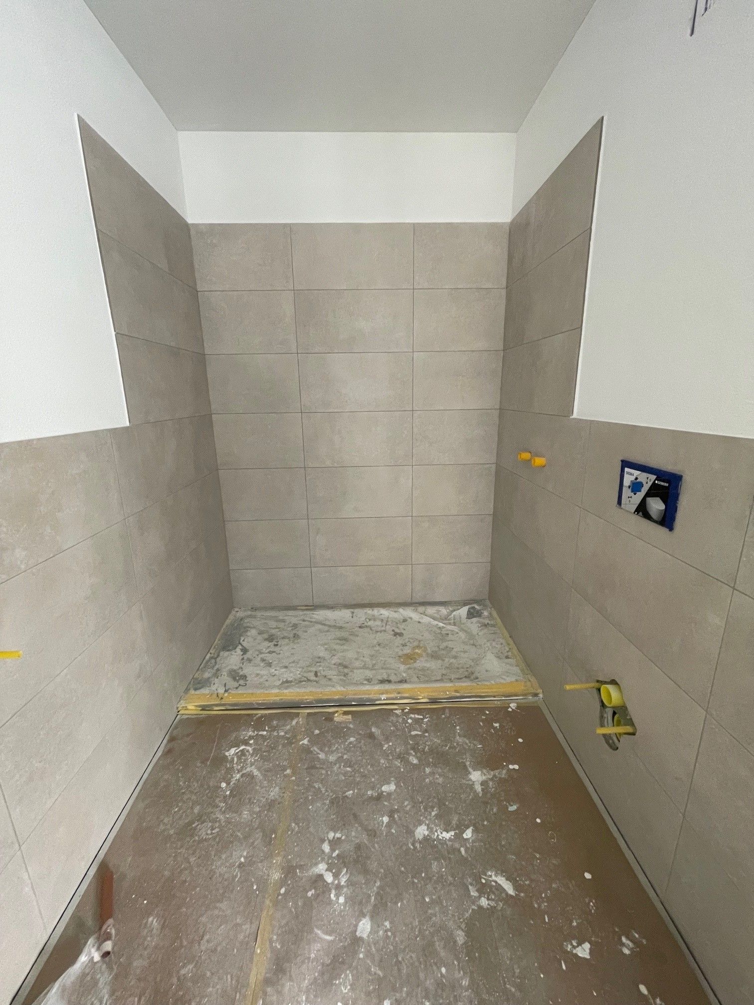 Ein im Bau befindliches Badezimmer mit Fliesen an Wand und Boden.