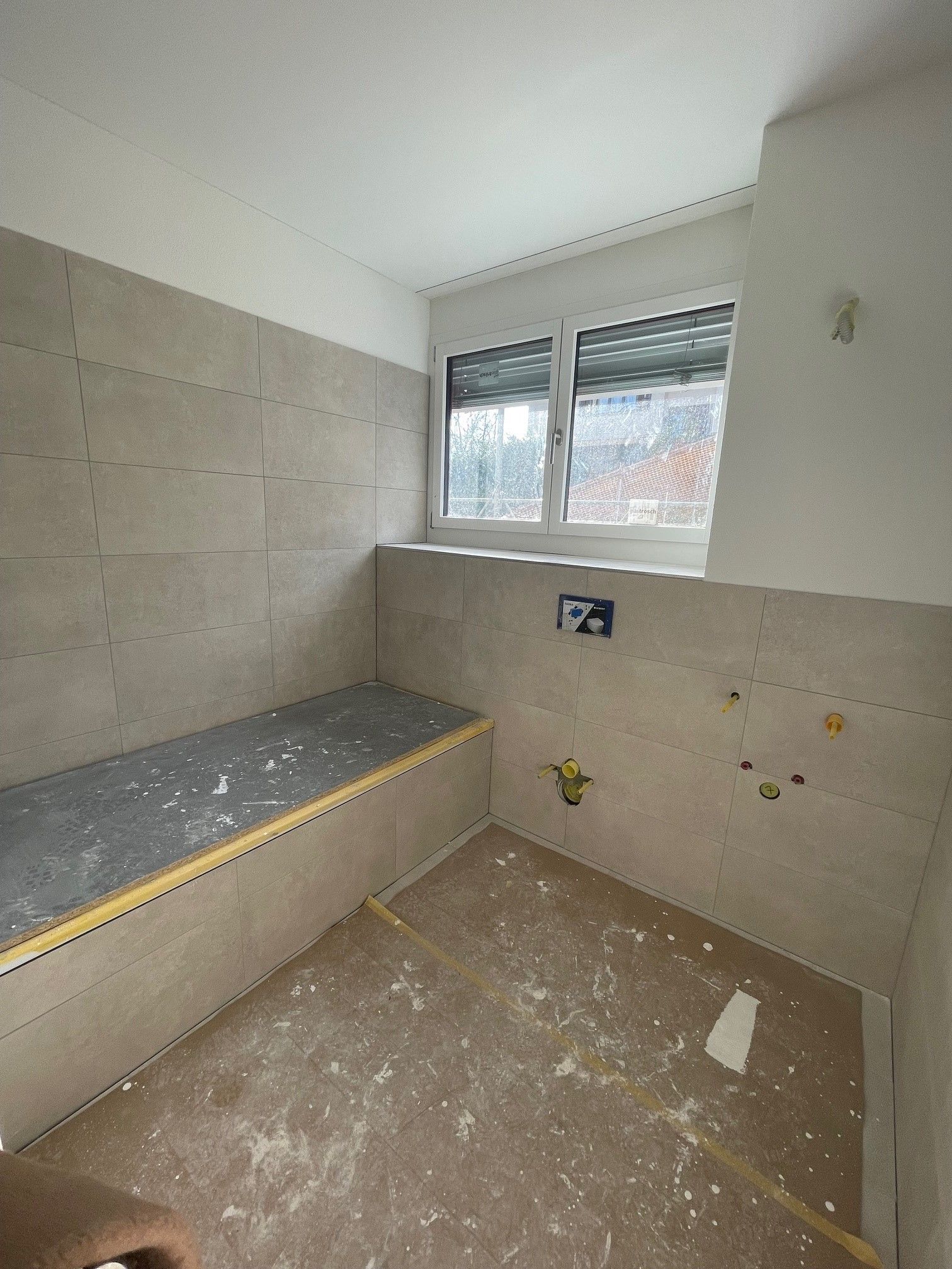 Ein im Bau befindliches Badezimmer mit einem Fenster und einer Bank.