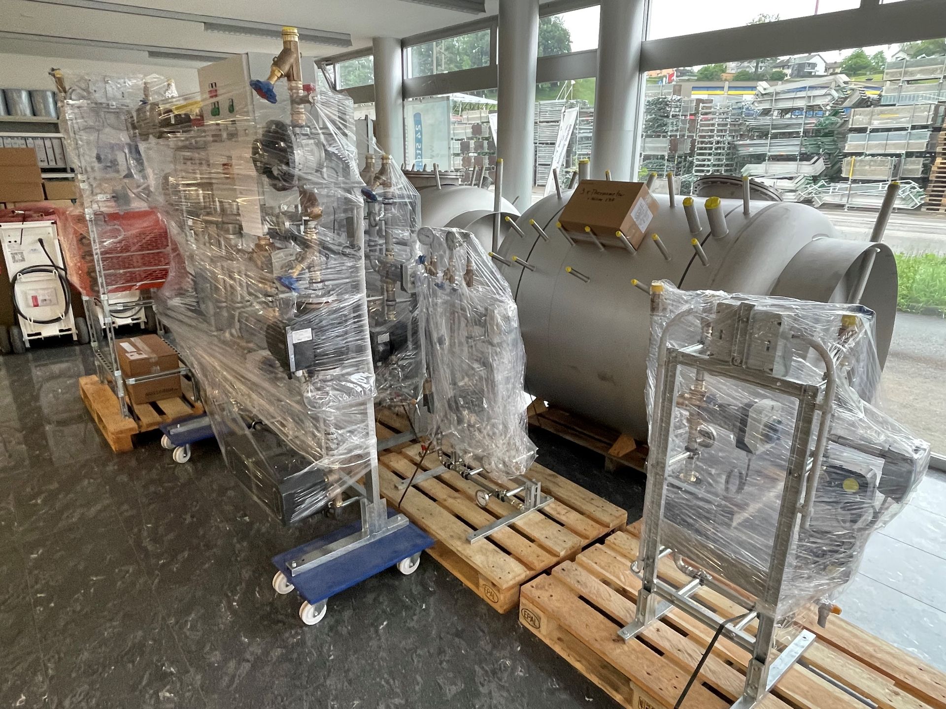 Eine große Maschine ist in Plastik eingewickelt und steht auf Holzpaletten.