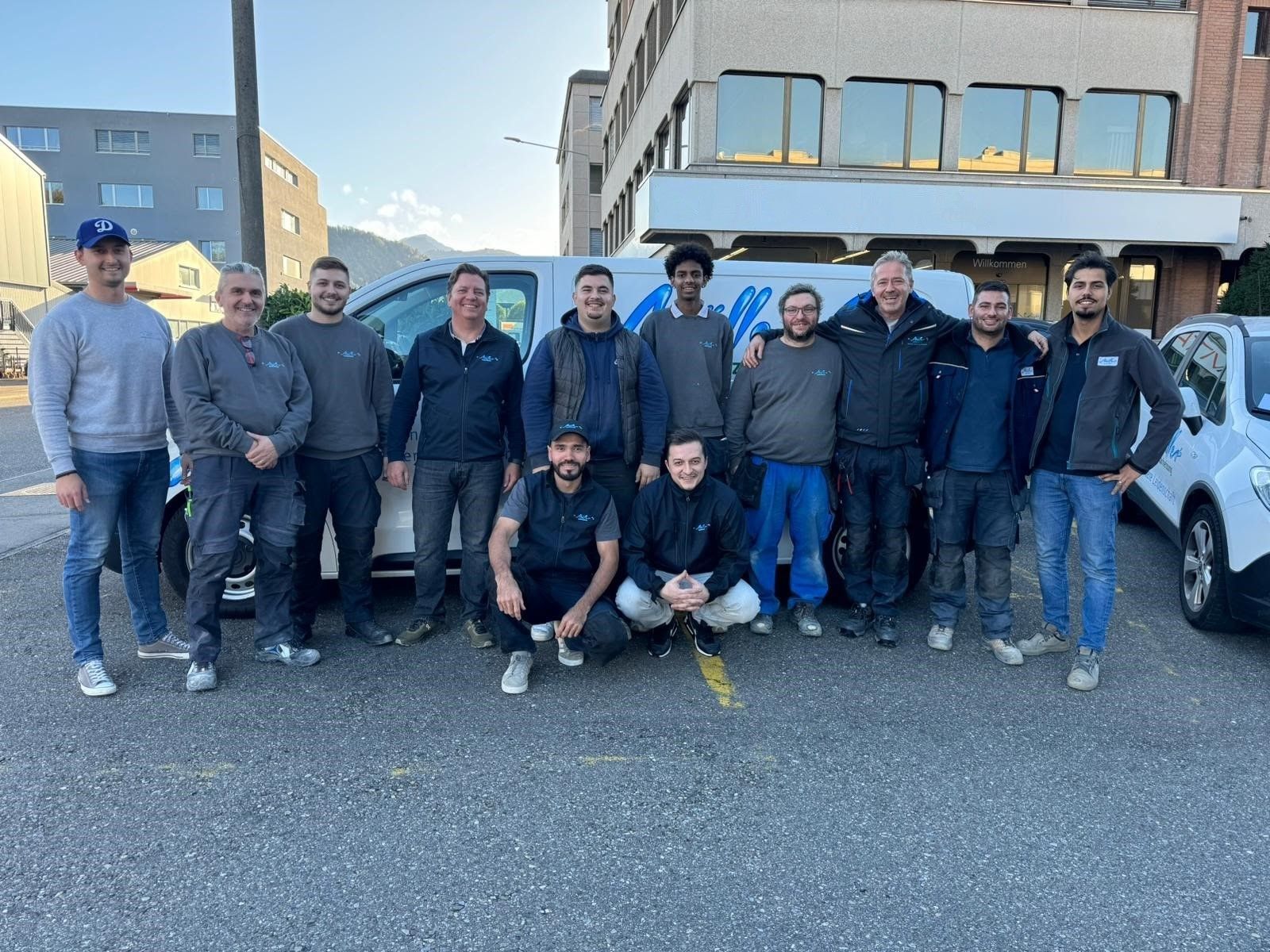 Eine Gruppe Männer posiert vor einem weißen Lieferwagen für ein Foto.