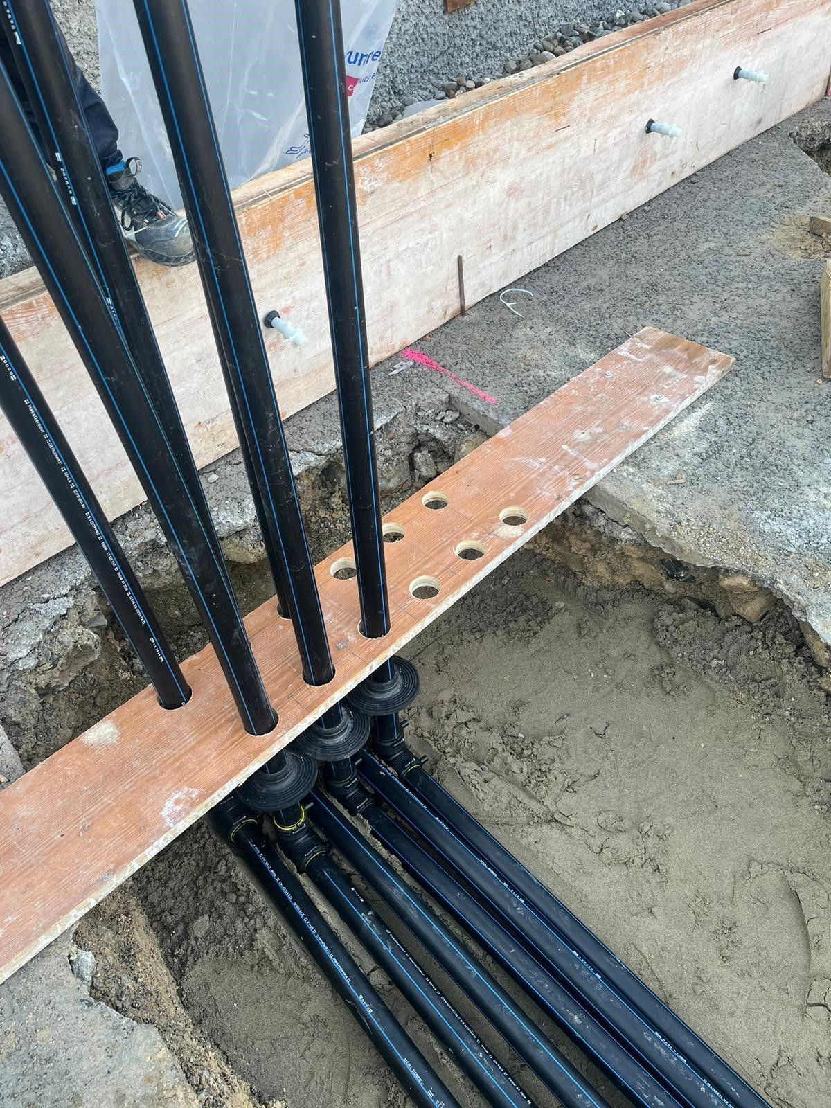 Ein Bündel schwarzer Rohre liegt auf einem Holzbrett.