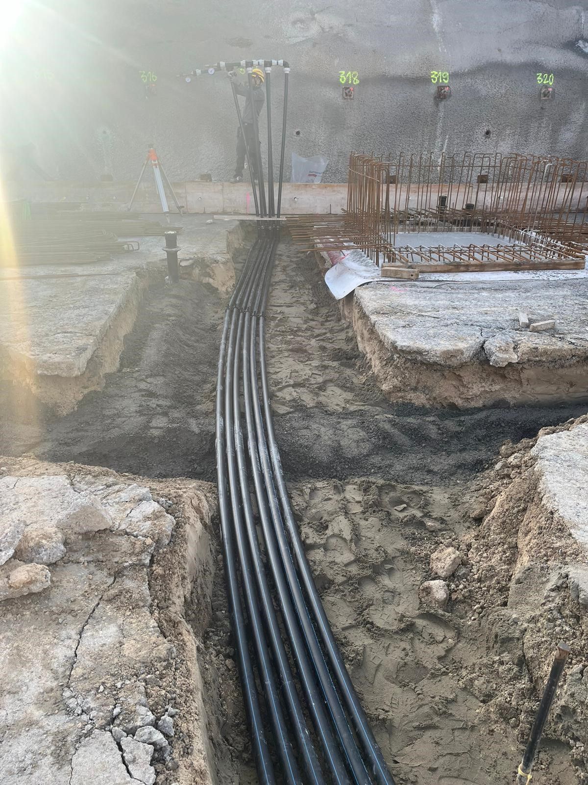 Ein Haufen schwarzer Rohre liegt im Dreck.