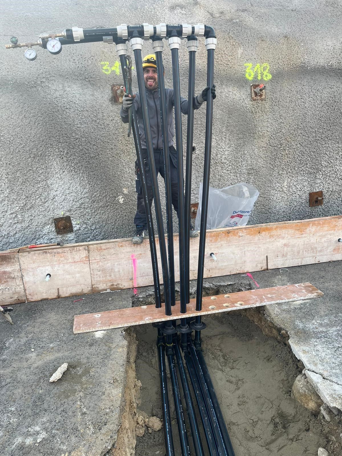 Ein Mann steht auf einer Baustelle neben einem Haufen Rohre.