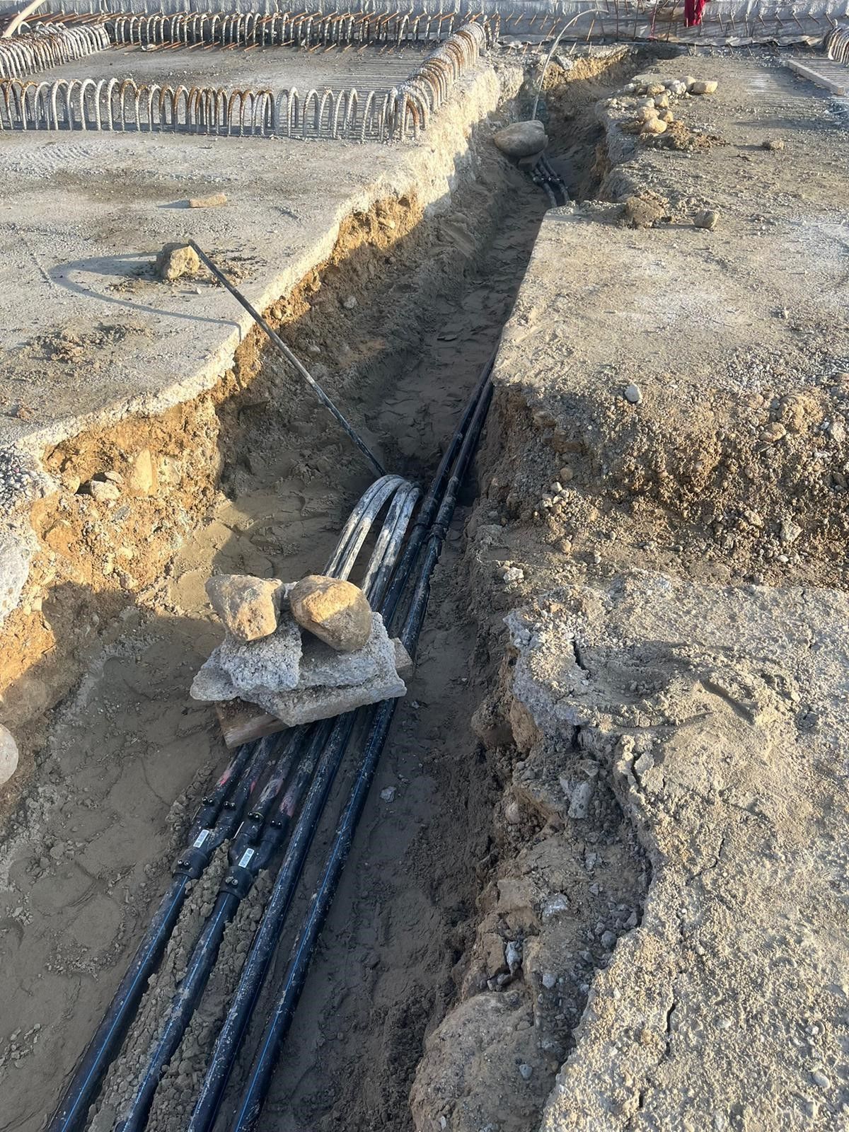 Auf einer Baustelle liegt ein Bündel Kabel im Dreck.