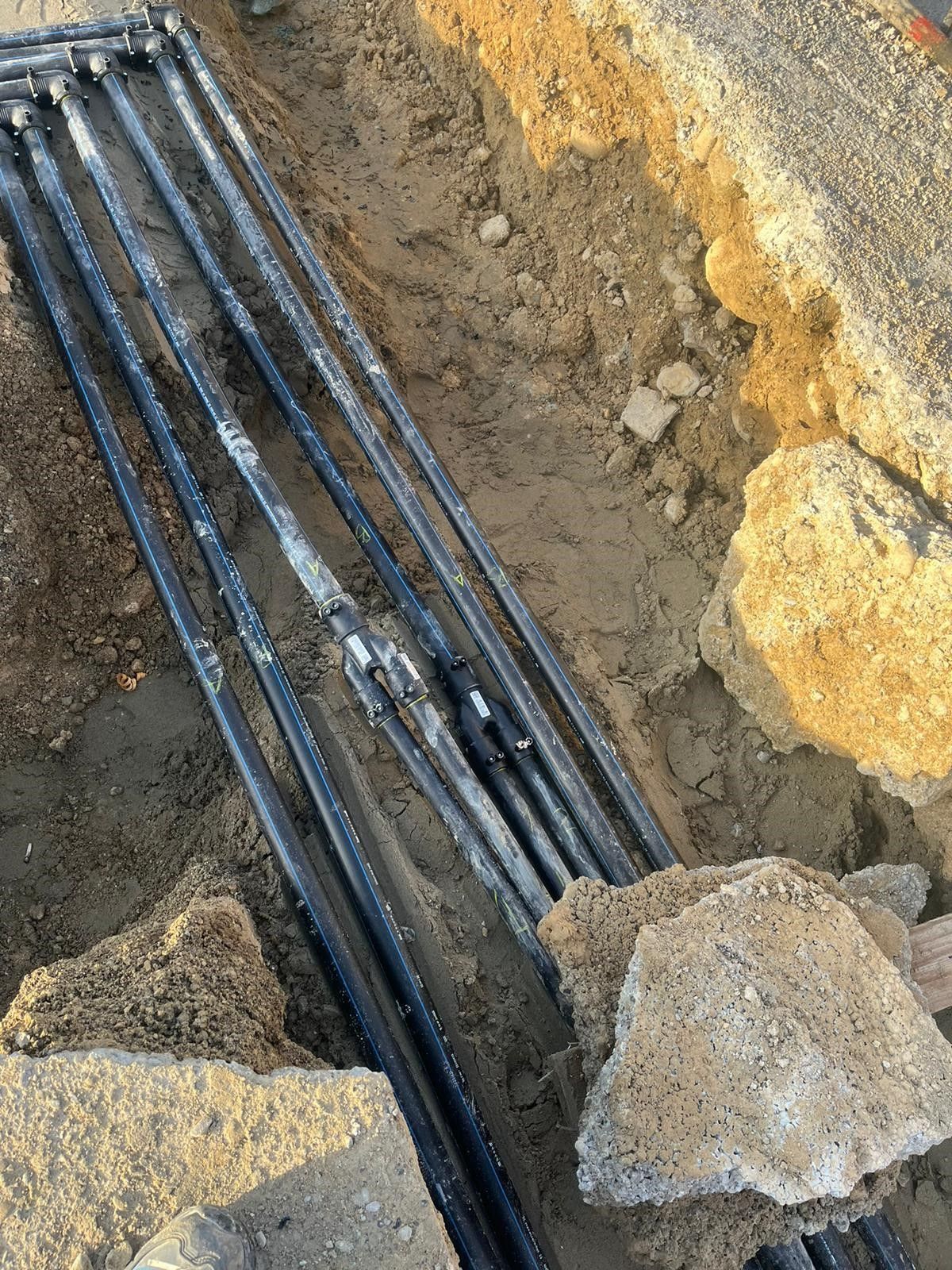 Ein Haufen schwarzer Rohre liegt im Dreck.