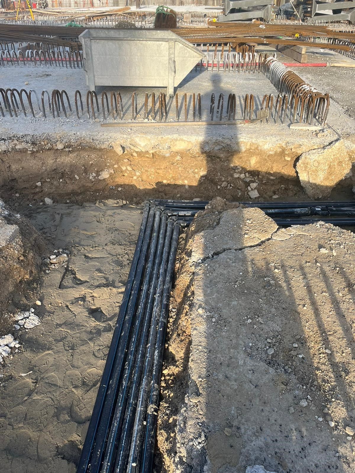 Auf einer Baustelle liegt ein Bündel Kabel im Dreck.