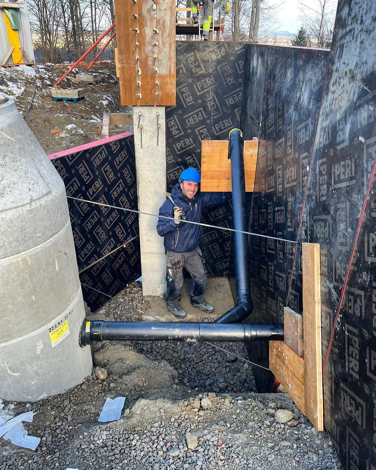 Ein Mann steht auf einer Baustelle neben einem Rohr.