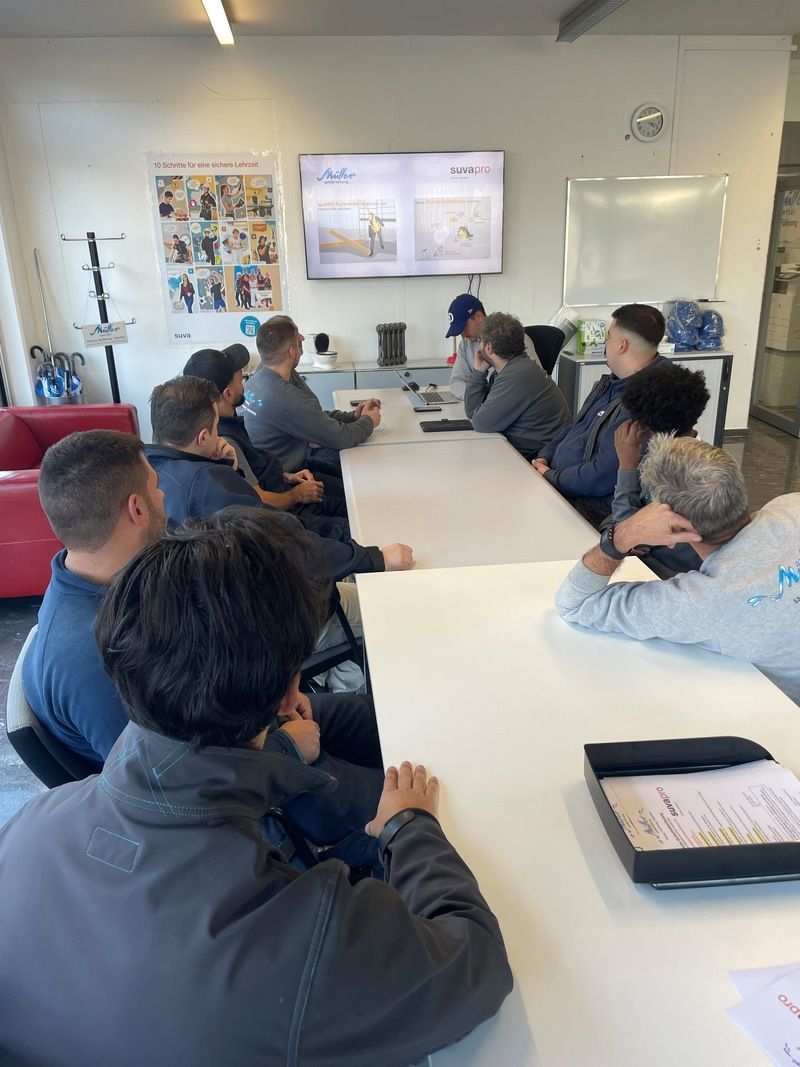 Eine Gruppe von Leuten sitzt in einem Konferenzraum um einen Tisch herum.