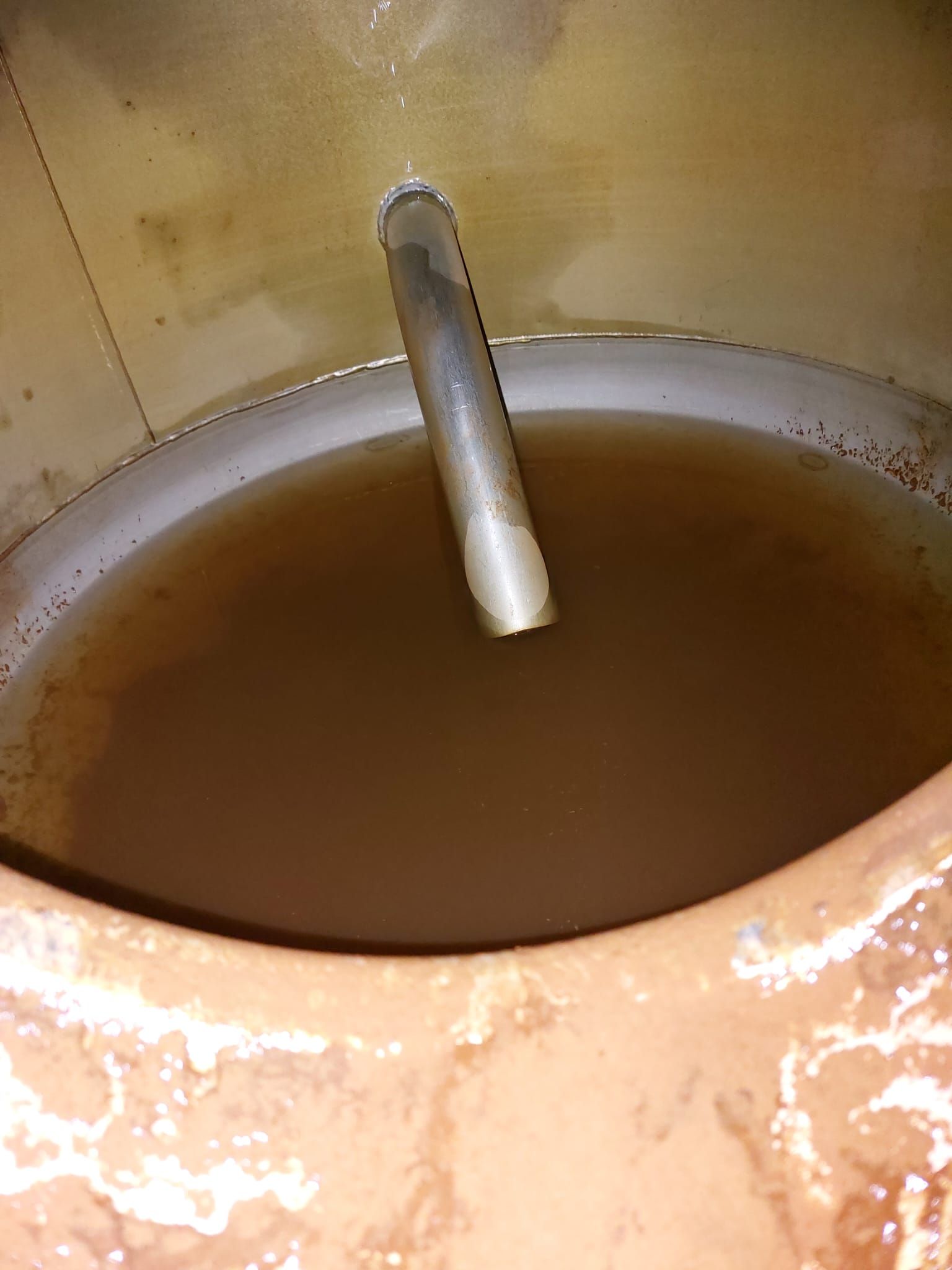 Ein Metallrohr ragt aus einem Tank mit brauner Flüssigkeit