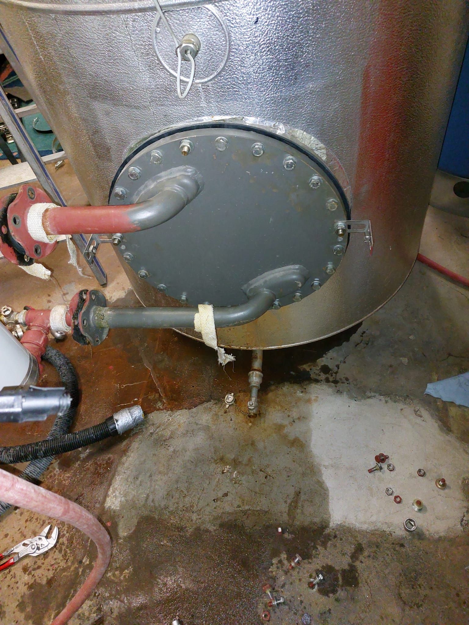 Ein Warmwasserbereiter steht neben einem Schlauch auf dem Boden.