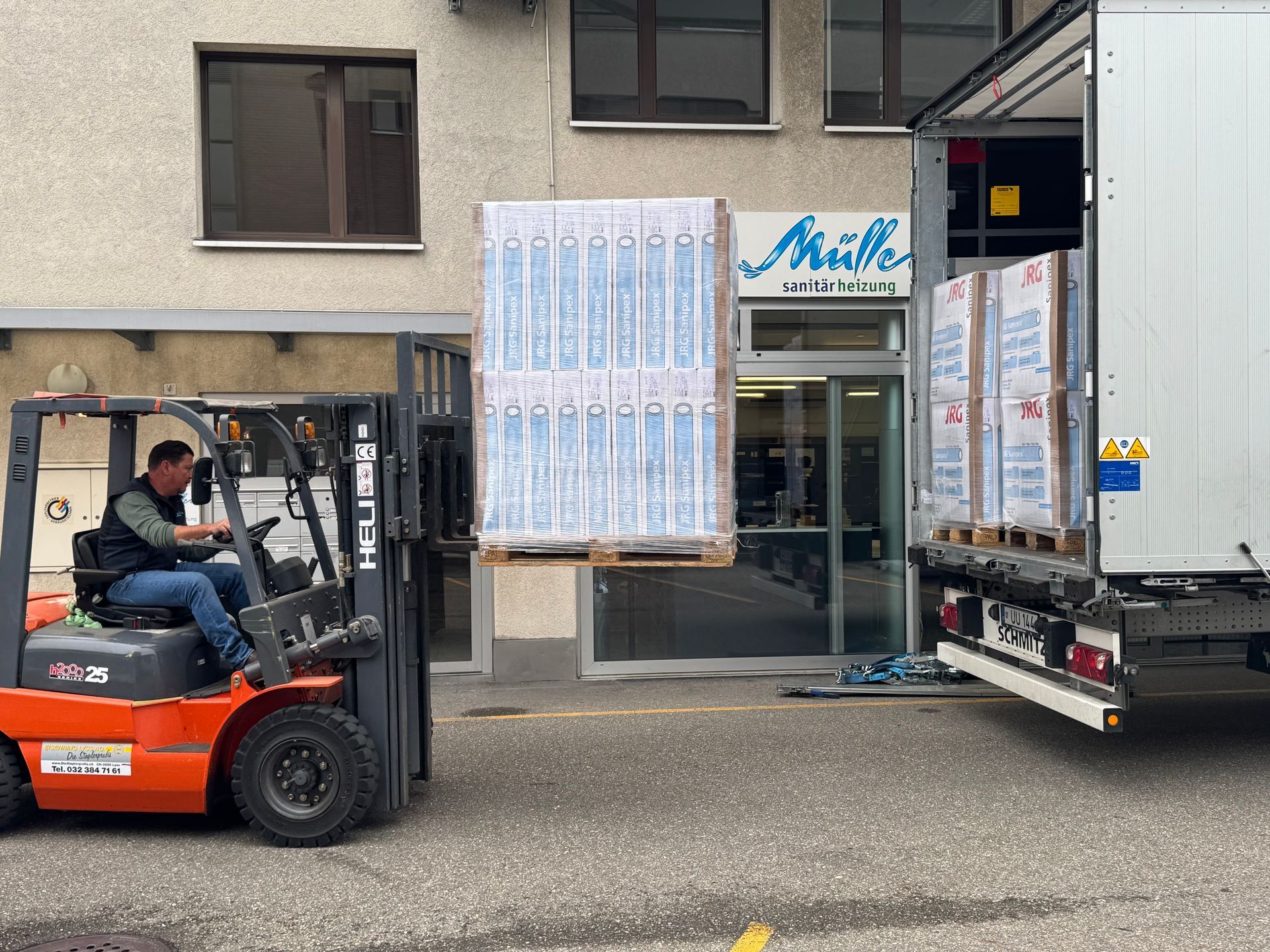 Ein Mann fährt einen Gabelstapler vor einem Gebäude