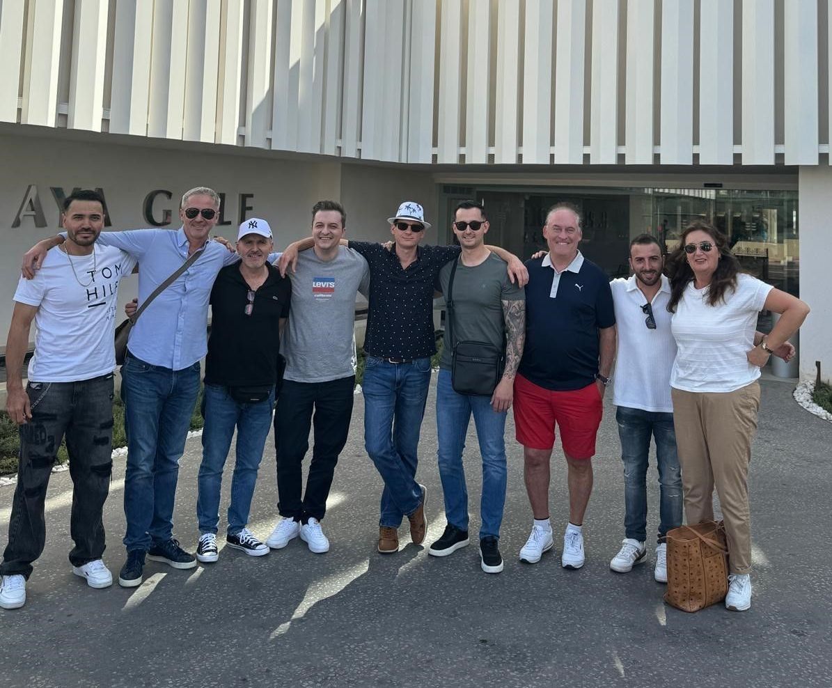 Eine Gruppe von Menschen posiert vor einem Golfplatz für ein Foto.