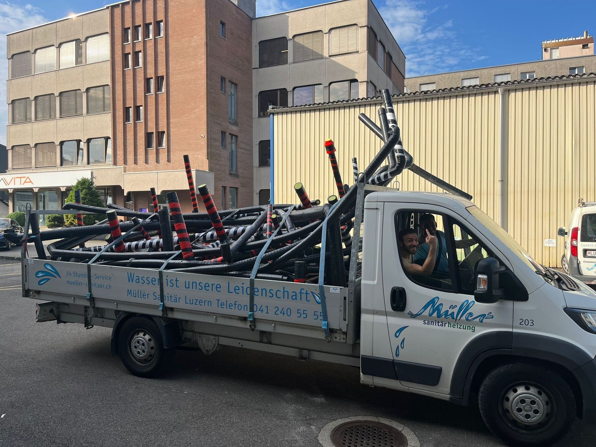 Ein weißer Lieferwagen ist mit einem Haufen Rohre beladen