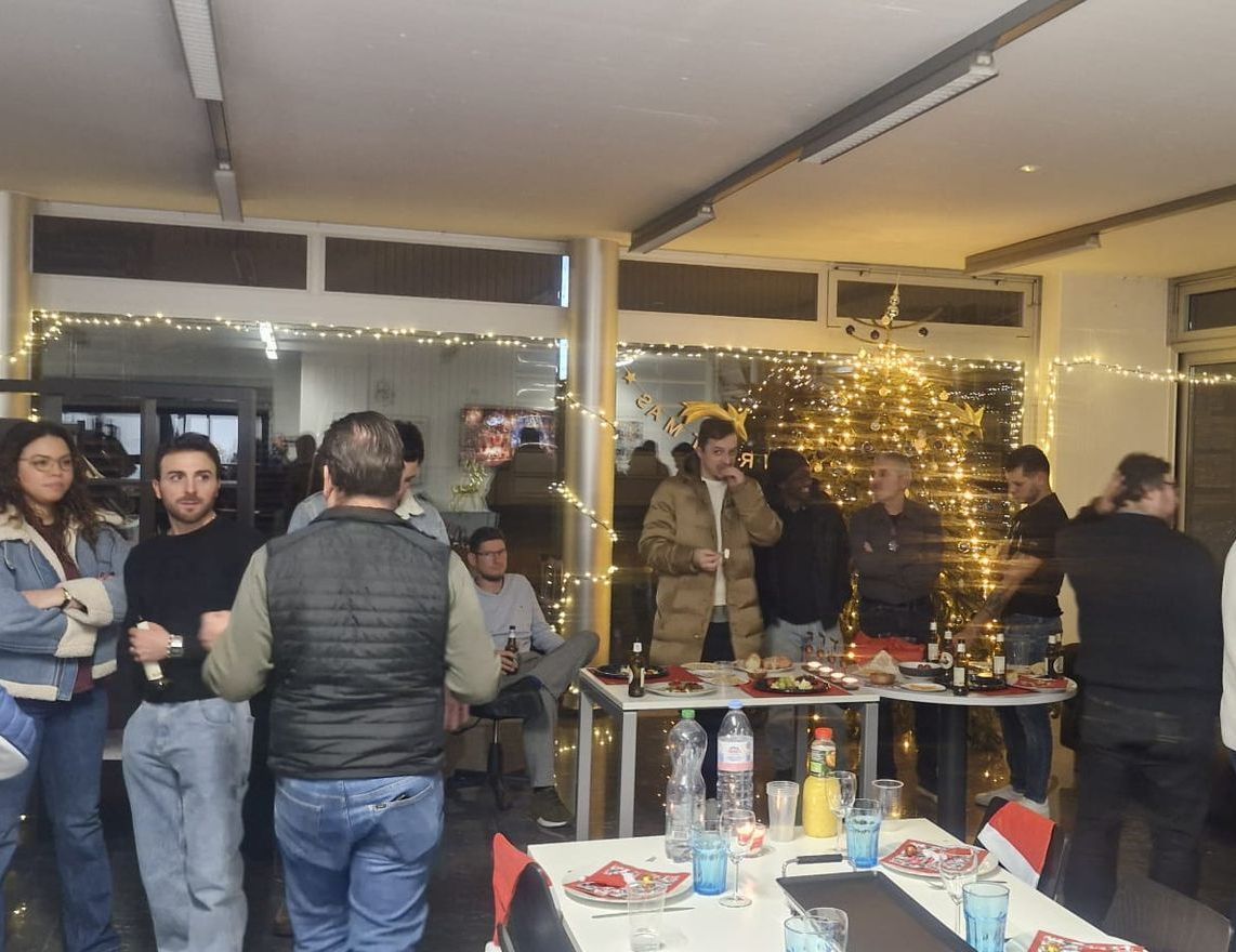 Eine Gruppe von Menschen, die in einem Raum um Tische herumstehen