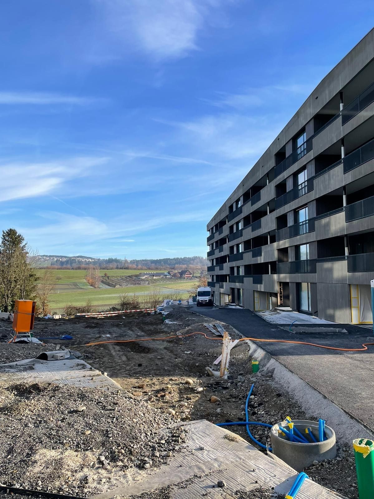 Mitten auf einem Feld wird ein großes Gebäude errichtet.