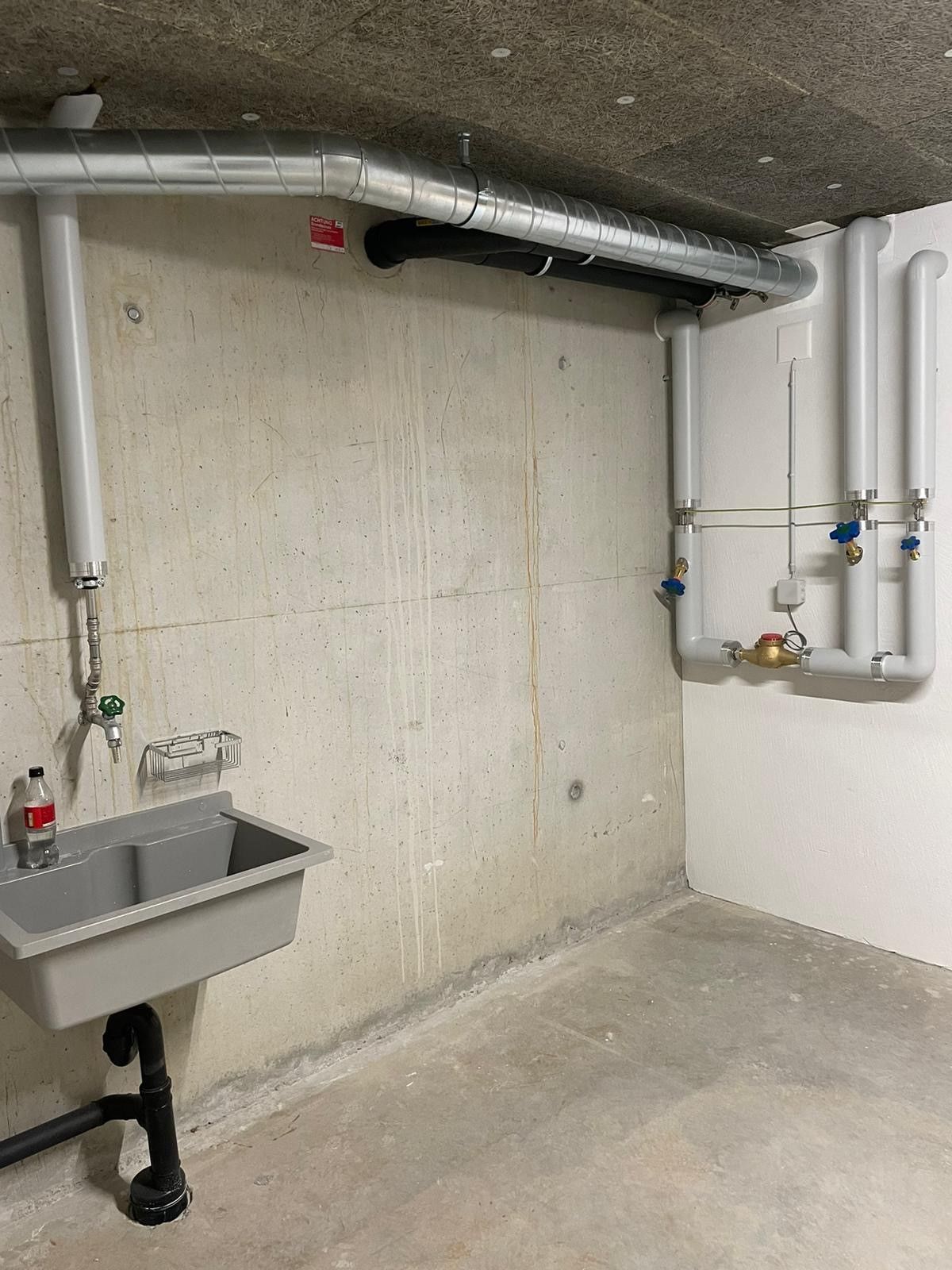Ein Raum mit einem Waschbecken und Rohren an der Wand.