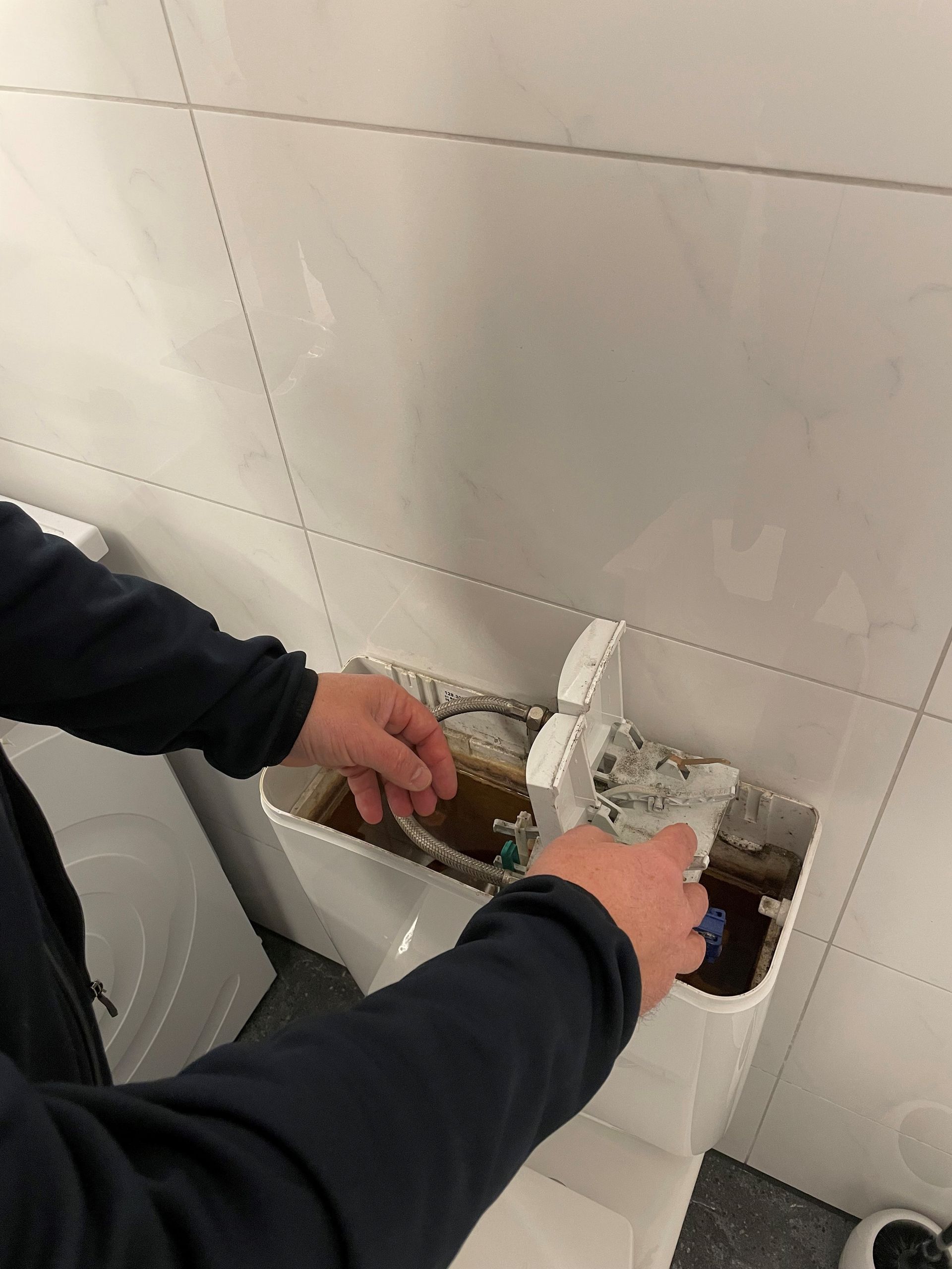 Eine Person reinigt eine Toilette in einem Badezimmer.