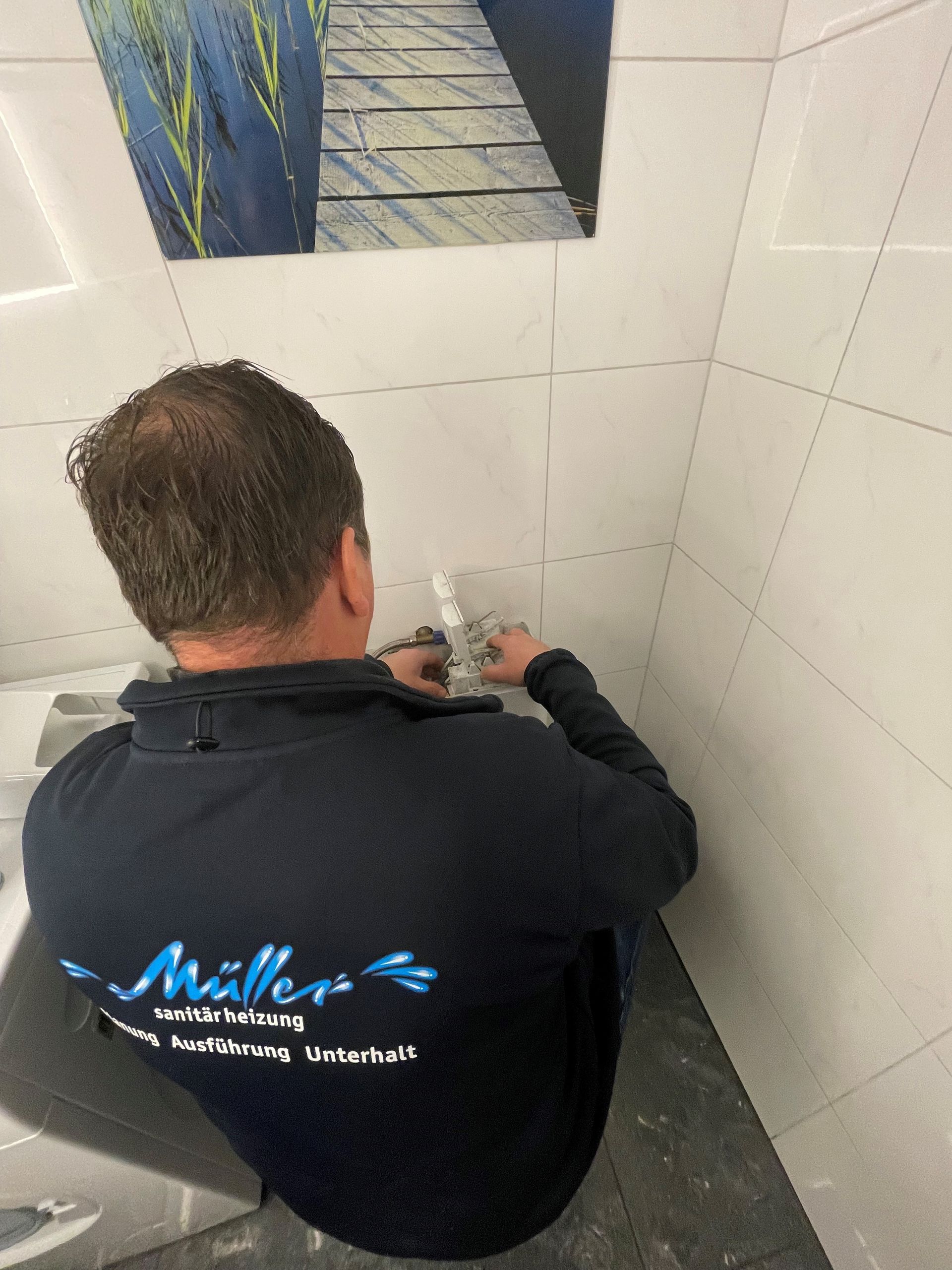 Ein Mann in einem blauen Hemd sitzt auf einer Toilette in einem Badezimmer.