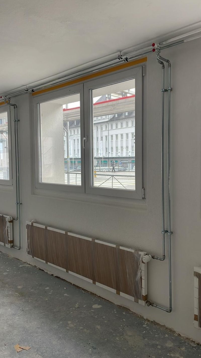 Ein Raum mit vielen Fenstern und Heizkörpern an der Wand.
