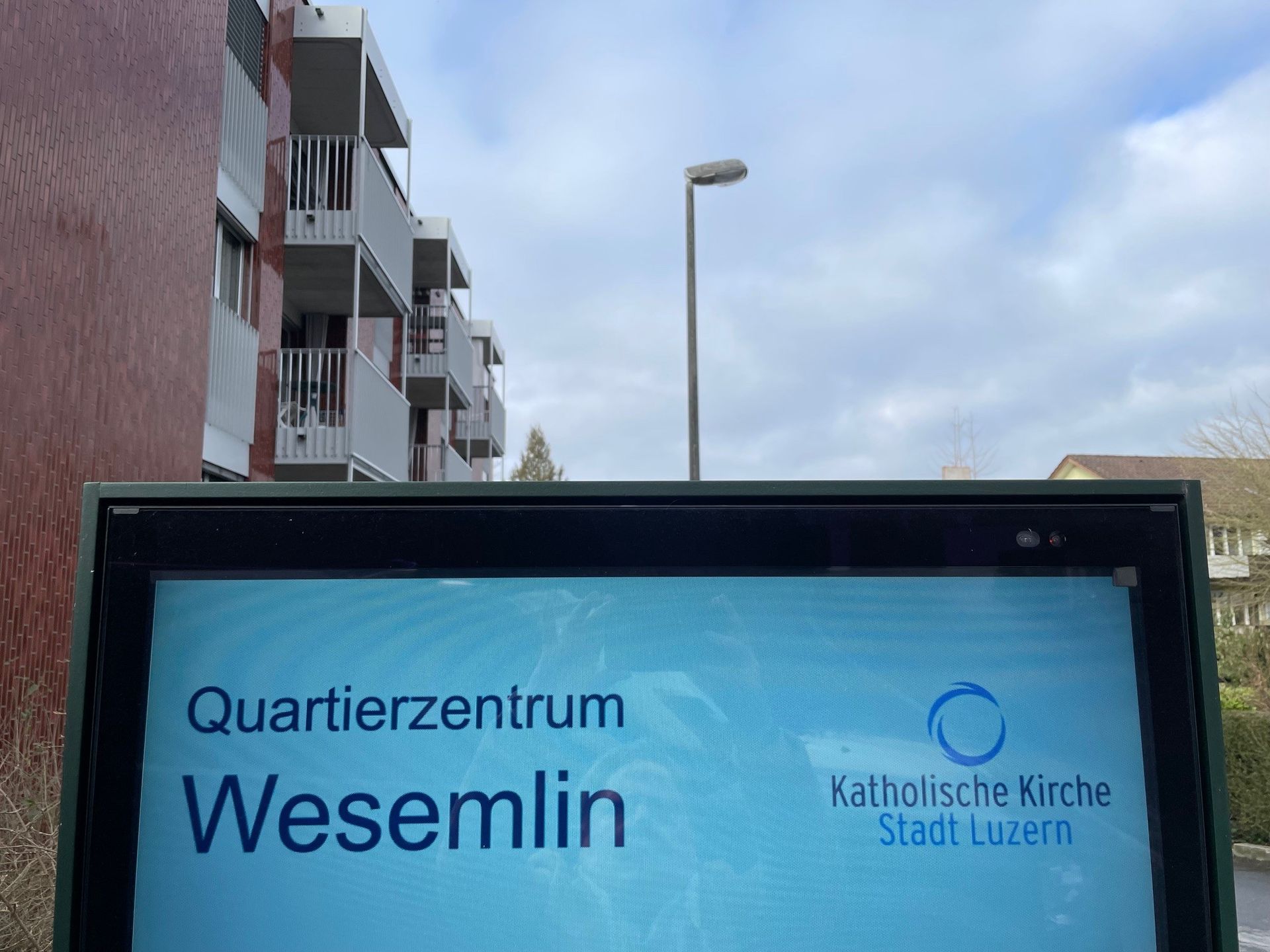 Vor einem Gebäude steht ein Schild mit der Aufschrift „Quartierzentrum Wesemlin“.