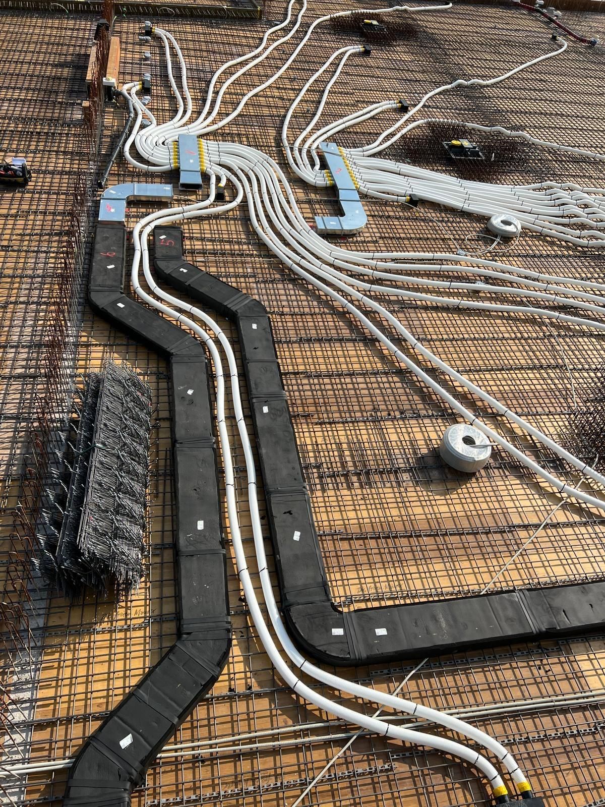 Auf einer Baustelle liegt ein Bündel Kabel auf dem Boden.