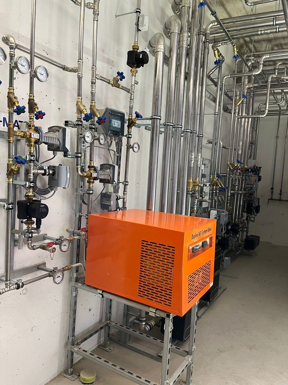 Ein Raum voller Rohre und einer großen orangefarbenen Kiste.