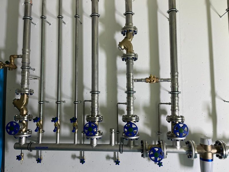 Eine Reihe von Edelstahlrohren mit daran befestigten blauen Ventilen