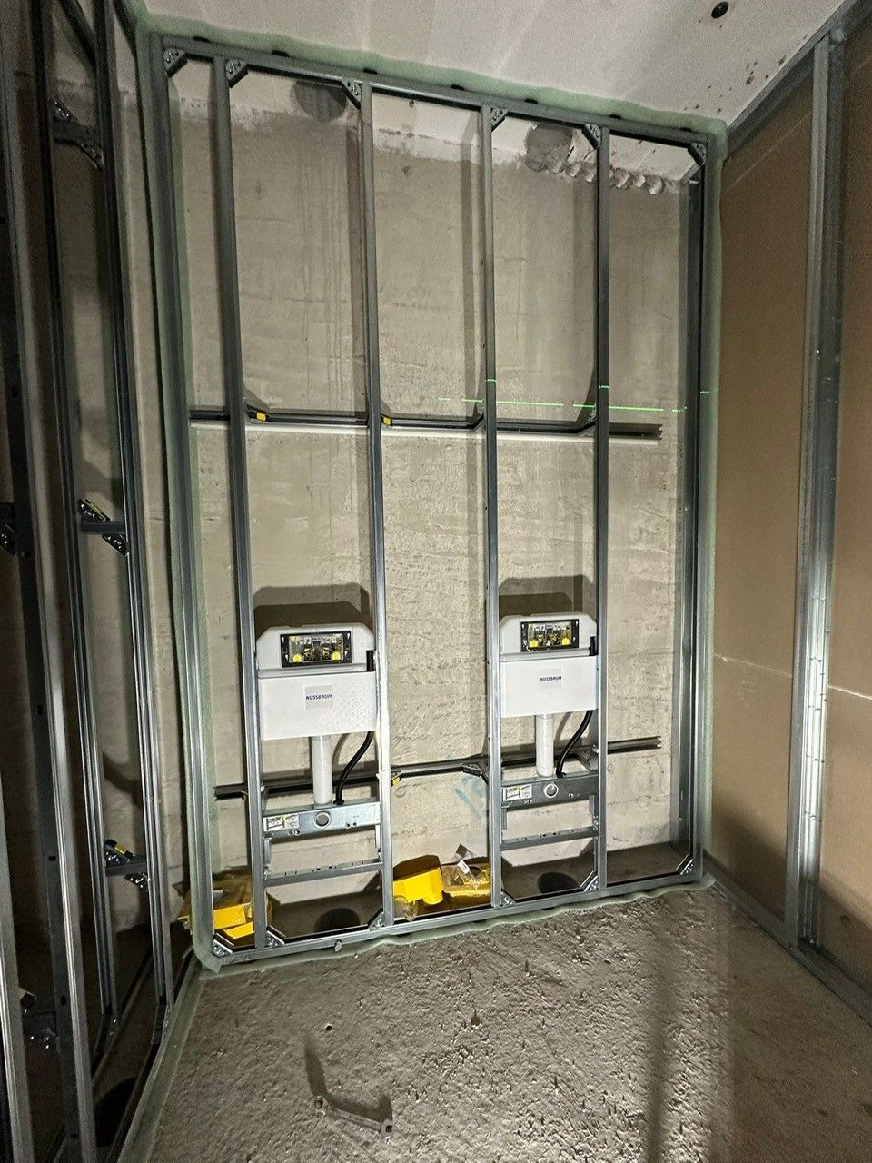 Ein im Bau befindliches Badezimmer mit zwei Toiletten in der Wand.