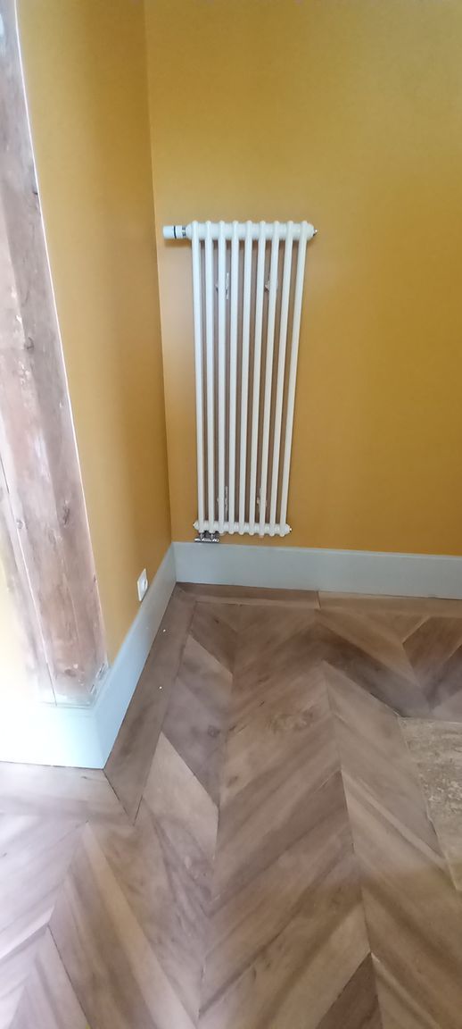Un radiateur sur un mur jaune.