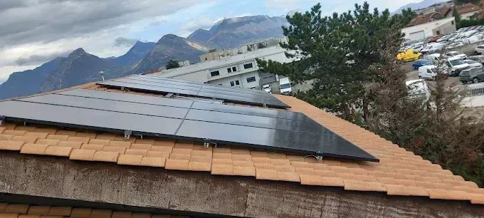 Panneaux solaires sur un toit en pente, avec des montagnes en arrière-plan.