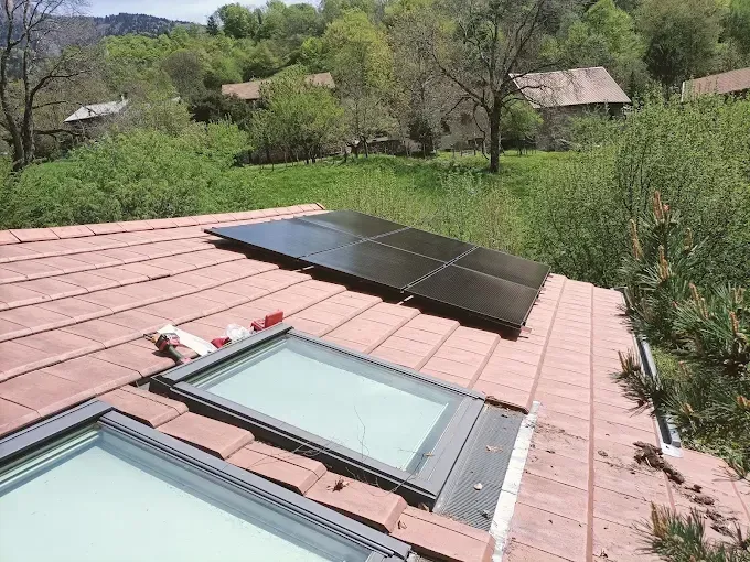 Toit avec puits de lumière et panneaux solaires donnant sur un paysage rural verdoyant