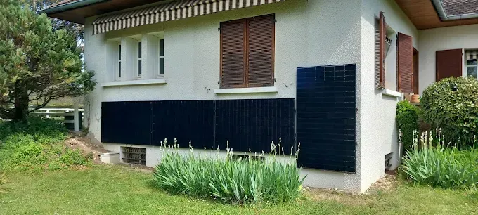 Maison blanche avec volets bleu foncé et jardin gazonné devant.