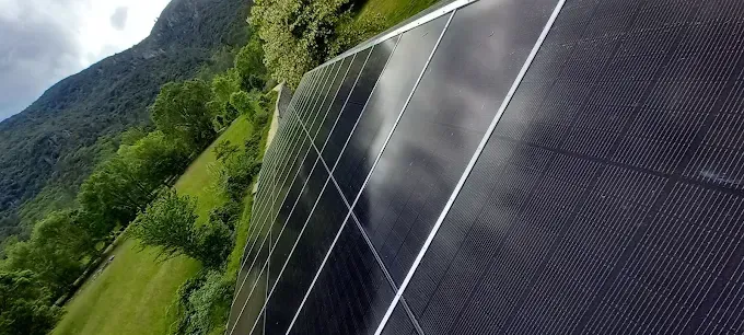 Des panneaux solaires sur une colline verdoyante avec des montagnes en arrière-plan