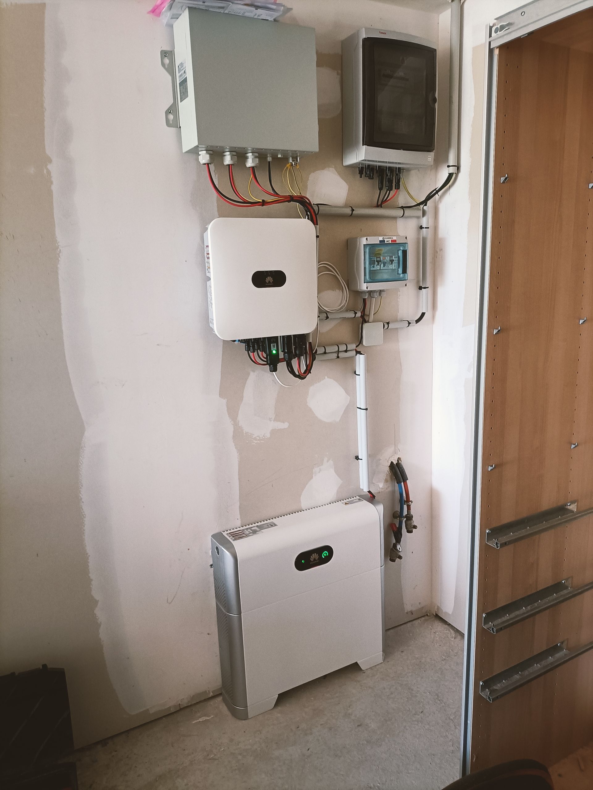 Boîtes et panneaux électriques muraux au-dessus d'une armoire blanche dans une petite buanderie