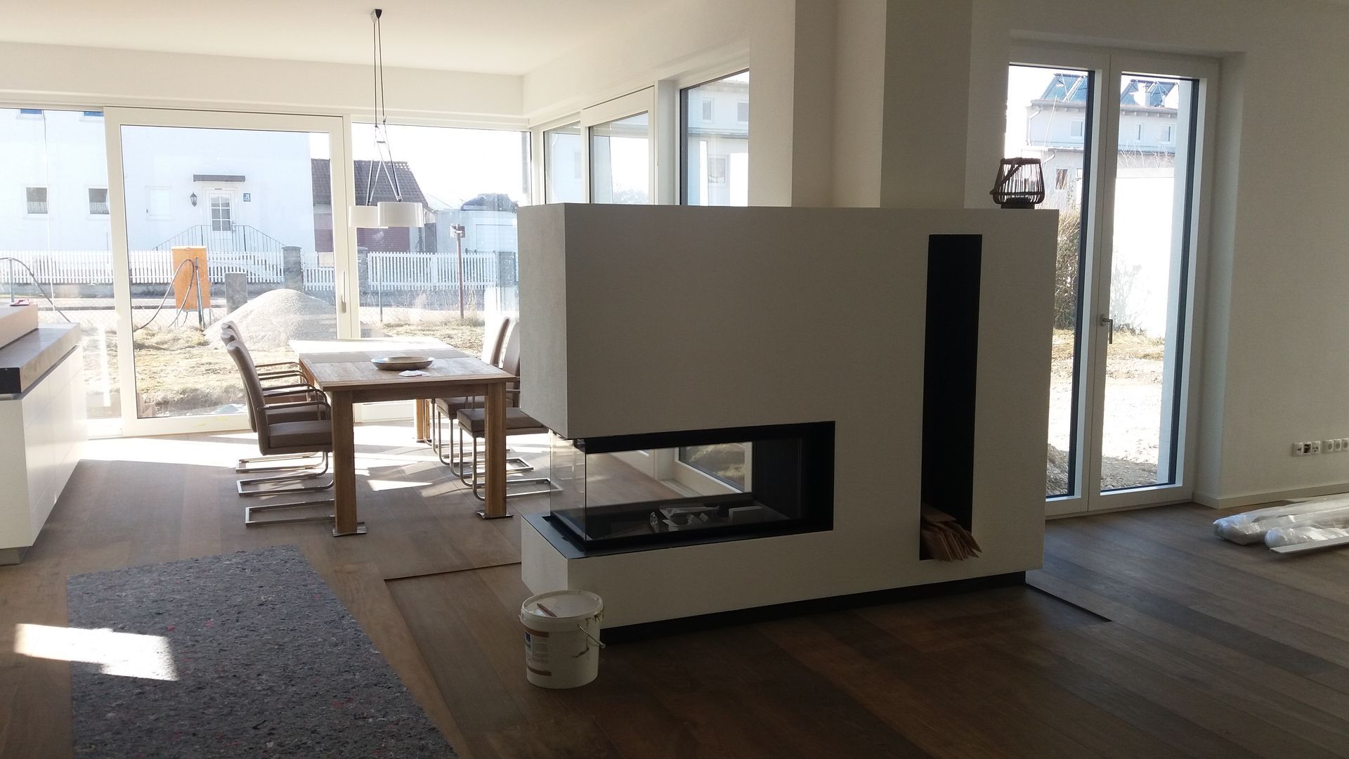Modernes Wohnzimmer mit weißem Kamin und großen Fenstern mit Blick auf eine Terrasse