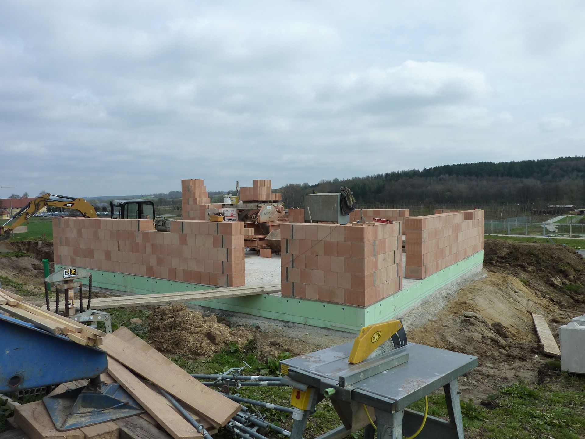 Ein teilweise fertiggestelltes Backsteinhaus auf einer Baustelle unter bewölktem Himmel