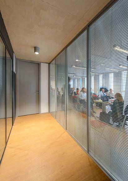 Salle couloir avec une salle de bureau séparée par des vitres et des rideaux