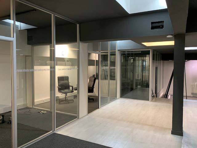 Couloir de bureau avec pièces séparées par une cloison vitrée