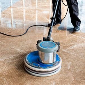Persona puliendo un piso de mármol con una pulidora eléctrica.
