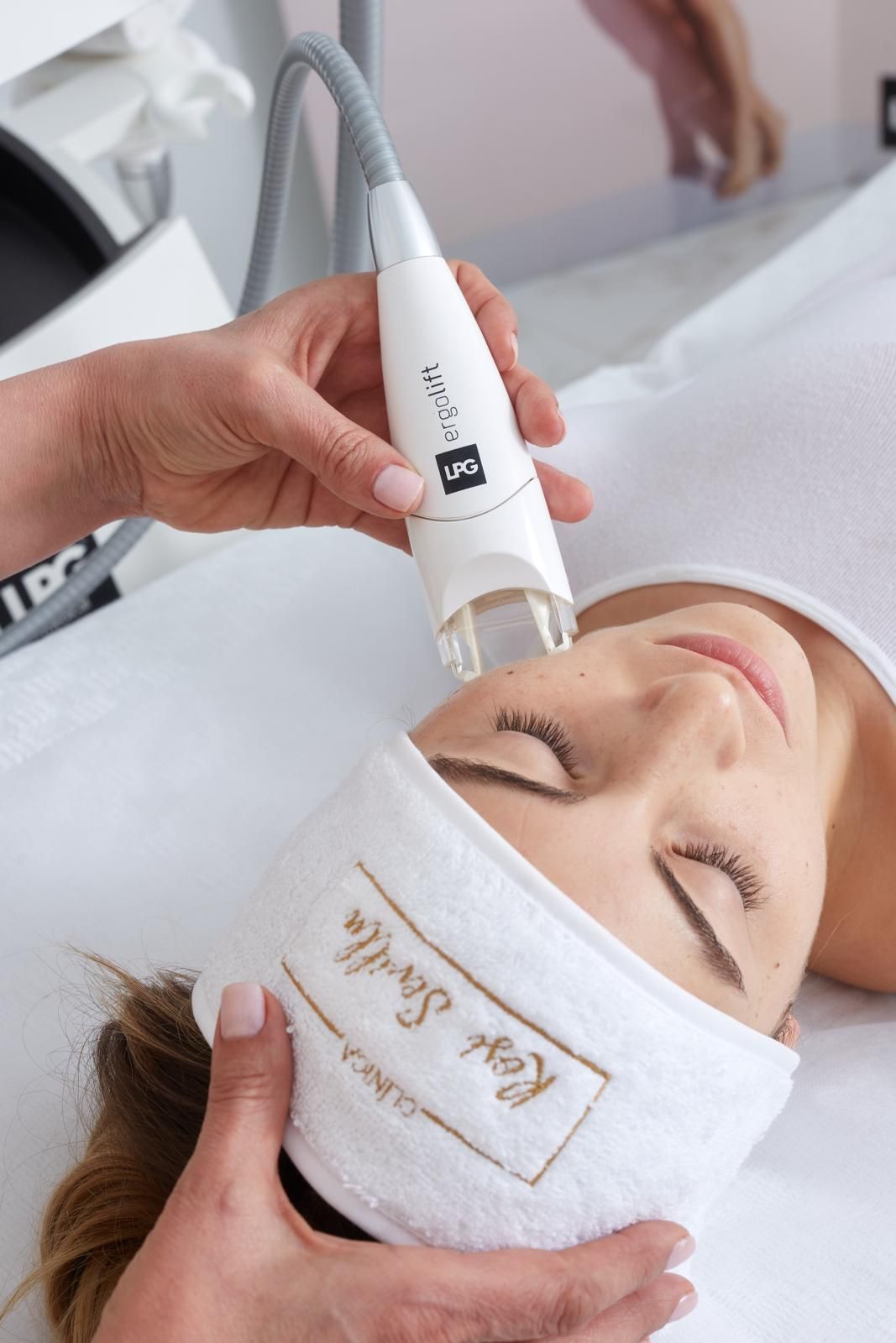 Una esteticista profesional utiliza un dispositivo médico portátil para realizar un tratamiento facial en la piel de la clienta.