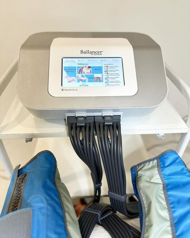 Un dispositivo de terapia de compresión Balancer Pro sobre un carrito con tubos conectados a mangas inflables azules para las piernas.