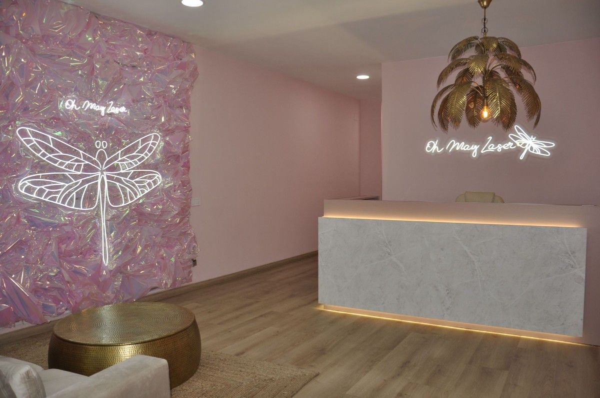 Un área de recepción con un letrero de neón de libélula en la pared.