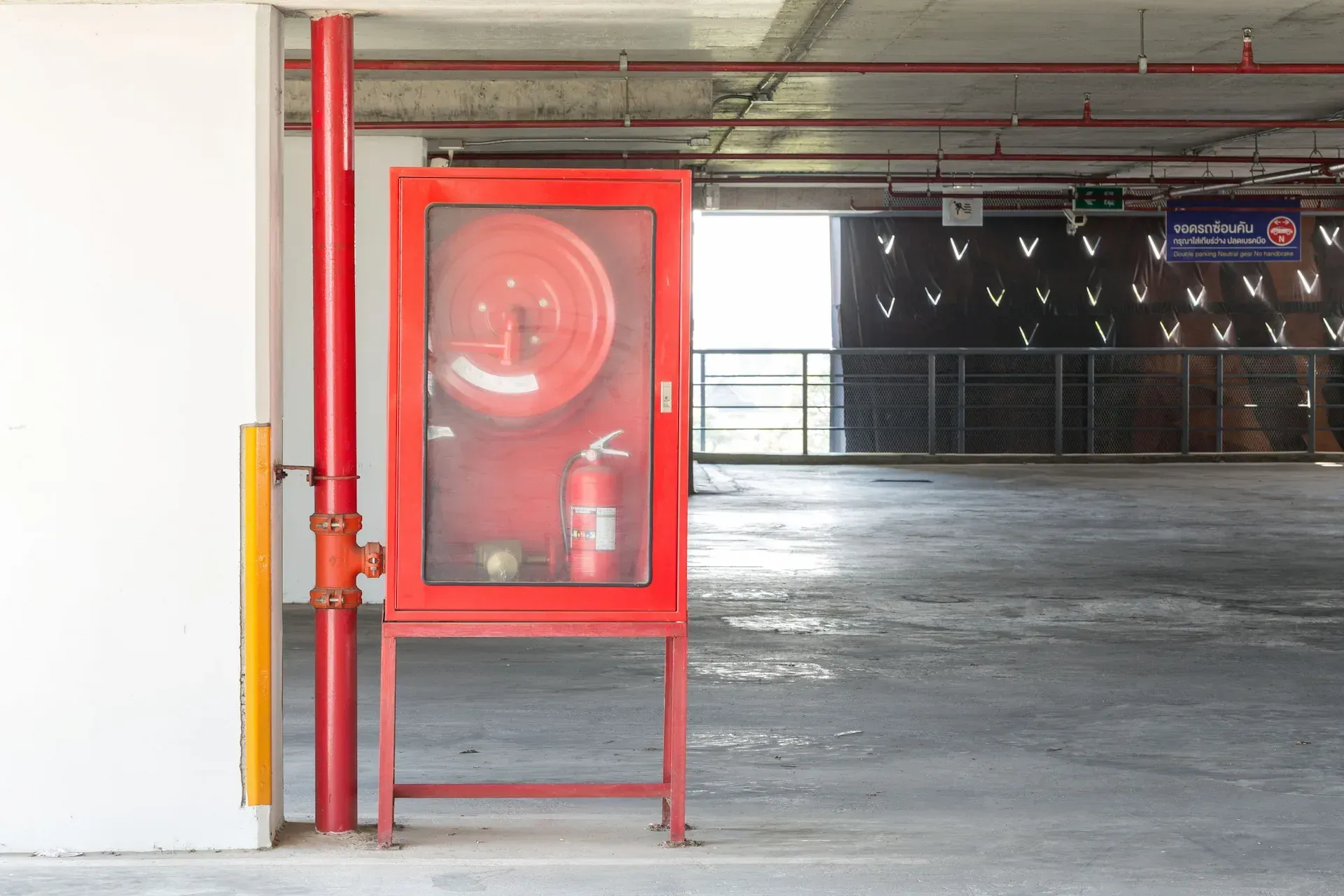 Vista exterior de un edificio con tuberías rojas y plateadas, escaleras y paredes grises.