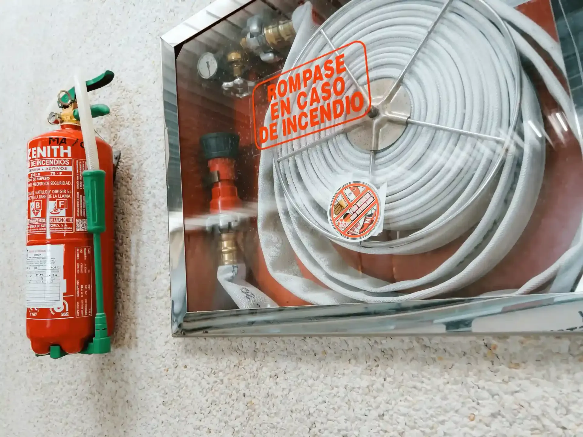 Armario para extintor y manguera contra incendios en una pared.