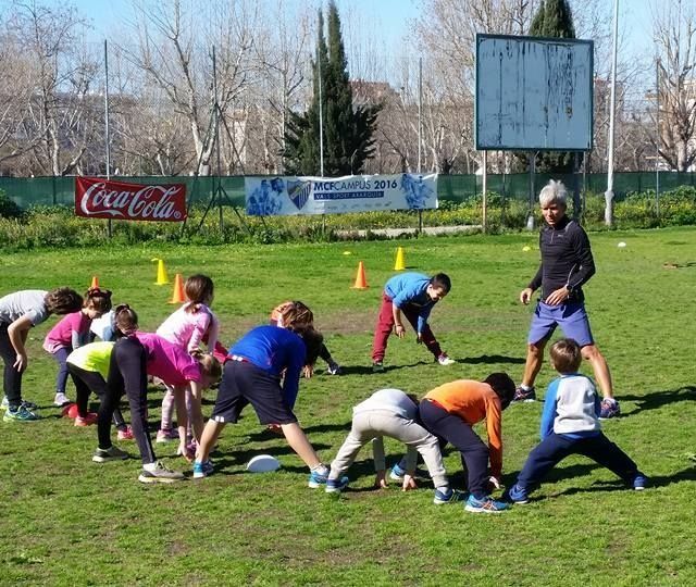 Un grupo de niños se estira en un campo con un cartel de Coca Cola al fondo.