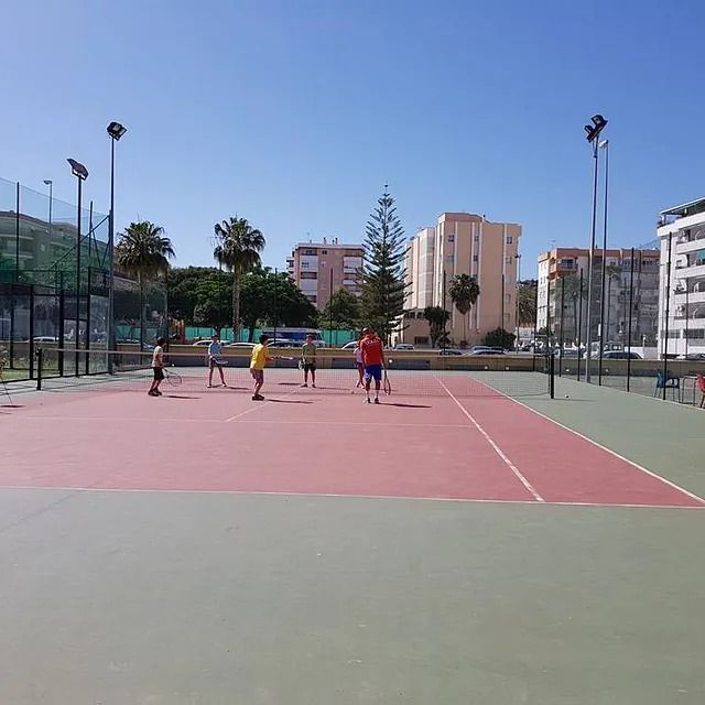 Un grupo de personas está jugando voleibol en una cancha de tenis.