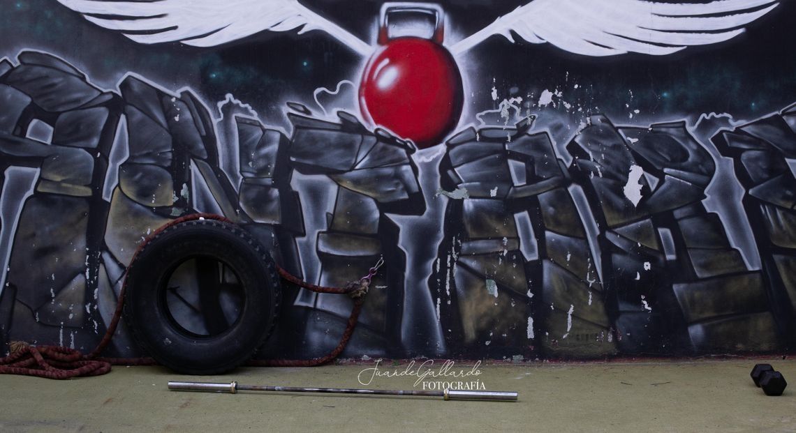 Una pared de graffitis con un neumático y una barra delante.